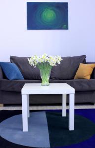 a white coffee table with a vase of flowers on it at Zielona Przystań in Łódź