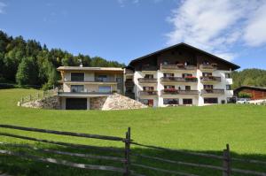 un grand bâtiment sur une colline avec une clôture dans l'établissement Residence Scheidnerhof, à Aldino