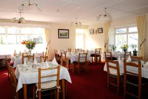 uma sala de jantar com mesas e cadeiras brancas em Sancta Maria Hotel em Lahinch