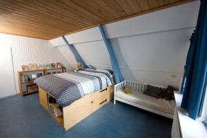 1 dormitorio con 1 cama grande y cortinas azules en B&B Molenstraat en Den Burg