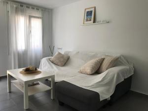 łóżko z białą pościelą i stołem w pokoju w obiekcie Apartamento Cánovas w mieście Tarifa