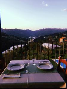 een tafel met borden en wijnglazen op een balkon bij Quinta De Calvelos in Vieira do Minho