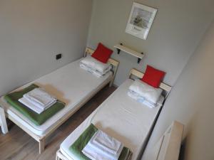 two beds in a small room with red pillows at Lake Vendégház in Alsóörs