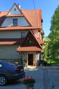 a car parked in front of a building with an orange roof at Noclegi Bukowina Centrum in Bukowina Tatrzańska