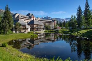a building next to a lake with mountains in the background at Alyeska Resort in Girdwood