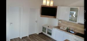 Una cocina con gabinetes blancos y un televisor de pantalla plana. en House Anica, en Starigrad-Paklenica