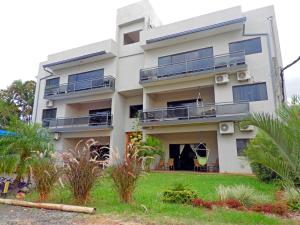 a white building with balconies and a yard at Hotel Puesta del Sol in Encarnación