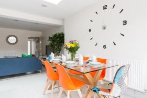uma sala de jantar com uma mesa de vidro e cadeiras laranja em Stunning Solihull Long Stays - 4 Bedrooms with 7 Separate Beds, 2 Baths, Garden & Driveway by Birmingham Contractor Stays em Birmingham