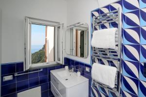 a blue and white bathroom with a sink and two windows at Admiring Amalfi in Scala
