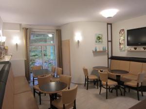 a dining room with tables and chairs and a tv at Hotel & Gasthaus Sterngrund in Zella-Mehlis