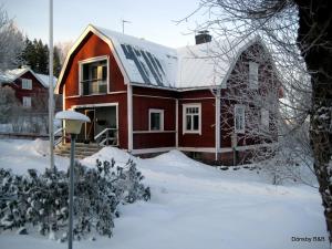 a red house with a roof in the snow at Villa Dönsby in Karjaa +25 photos