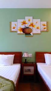 two beds in a room with paintings on the wall at Tabii hotel in Da Nang