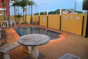 a stone table sitting next to a swimming pool at Bourbong St Motel in Bundaberg