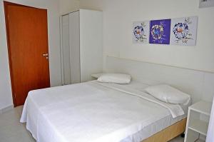 ein Schlafzimmer mit einem weißen Bett und einer Holztür in der Unterkunft Serra Park Apart in Rio Quente