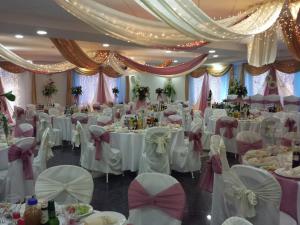 un salón de banquetes con mesas y sillas blancas en Parish Bull Hotel, en Kisvárda