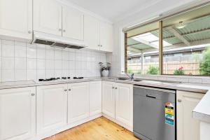 a kitchen with white cabinets and a window and a dishwasher at Maroondah 3 Bedroom house in Kilsyth in Kilsyth