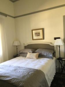a bedroom with a large white bed with two lamps at Kings Cottage Uralla in Uralla