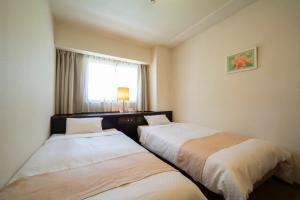 two beds in a hotel room with a window at Hotel S-plus Nagoya Sakae in Nagoya