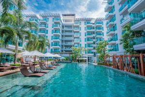 a swimming pool with chairs and a large building at Fishermens Harbour Urban Resort - SHA Extra Plus in Patong Beach