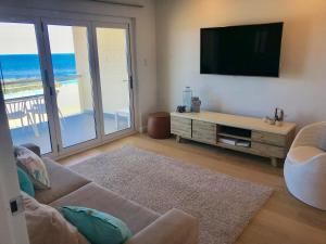 a living room with a couch and a flat screen tv at Cottesloe Beachfront Ocean View Apartment in Perth
