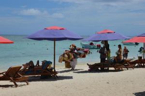 a beach with people sitting in chairs and umbrellas at Cazhibiscus in Trou aux Biches