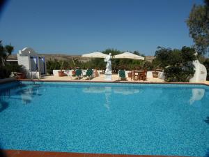 a large blue swimming pool with chairs and umbrellas at Oasi Di Casablanca in Lampedusa