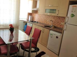 La cuisine est équipée d'une table, de chaises rouges et d'un réfrigérateur. dans l'établissement Fursan Apart, à Trabzon