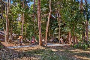 three people riding bikes down a path in a forest at Taj Exotica Resort & Spa, Andamans in Havelock Island
