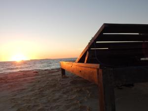 a piano sitting on the beach with the sunset at Shangri-la Lodge in Ambatomilo