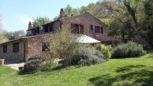 una vieja casa de piedra en un campo de hierba en Casa Vacanze Le Corone, en Otricoli