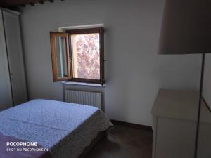 niewielka sypialnia z łóżkiem i oknem w obiekcie IMMERSA NEL VERDE w mieście Osimo