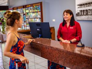 a woman standing at a counter talking to a customer at Hides Hotel in Cairns