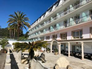 a large white building with palm trees in front of it at Hotel Nuevo Vichona Spa 3 estrellas Superior in Sanxenxo