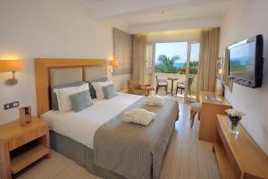 a hotel room with a large bed and a television at Olympic Lagoon Resort Ayia Napa in Ayia Napa