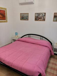 a bed with a pink comforter in a bedroom at Villa Walter in Oliena