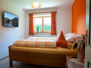 a bedroom with a bed with an orange wall at Ferienwohnung Ulrich Wurmser in Rottach-Egern
