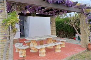 una mesa de picnic y bancos en un patio con flores en Bungalow Ramos III, en Conil de la Frontera 14 fotos más