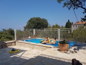 Due ragazze sono sedute in piscina di Villa Masha Brač a Bobovišća