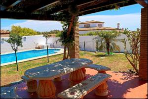 una mesa de picnic y dos bancos en un patio en Bungalow Ramos III, en Conil de la Frontera