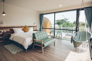 a bedroom with a bed and a chair and a balcony at Yellow's Kenting B&B in Nanwan