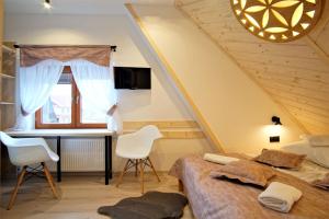 a bedroom with a bed and a desk and a window at U Janiny in Bukowina Tatrzańska