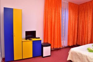 a bedroom with colorful curtains and a tv on a cabinet at Pensiunea La Safari in Tîrgu Neamţ