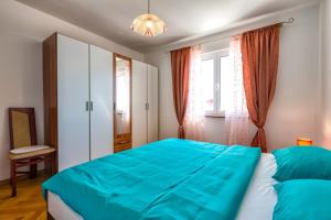 a bedroom with a blue bed and a window at Apartments Kira, Mali Lošinj in Mali Lošinj