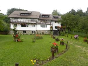 a house with a yard with flowers and plants at Pensiunea Cerbul Carpatin in Bran