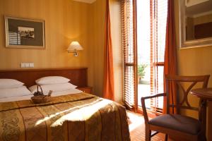 Hotel Willa Lubicz في غدينيا: غرفة نوم بسرير وكرسي ونافذة