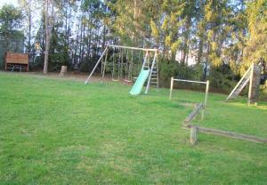 a playground with a swing set in a field at LOGIS Hôtel Le Moulin Des Gardelles in Riom