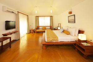 um quarto com uma cama grande e uma televisão em Le Pondy em Pondicherry