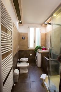uma casa de banho com 2 WC e uma cabina de duche em vidro. em Guasto Apartment em Bolonha