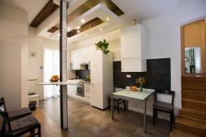 kuchnia z białymi szafkami, stołem i krzesłami w obiekcie Guasto Apartment w Bolonii