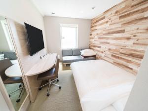 a bedroom with a bed and a desk with a computer at Super Hotel Kyoto Shijokawaramachi in Kyoto